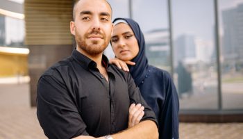 Portrait of a confident young Muslim couple standing together outside an urban building.